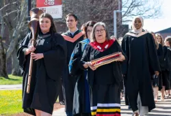Macebearer Katherine Guarino and Eagle Feather Bearer Dr. Judy Clark, Elder in Residence at UPEI, lead graduates in the faculties of Nursing and Veterinary Medicine into the Chi-Wan Young Sports Centre for their Convocation ceremony on May 14.