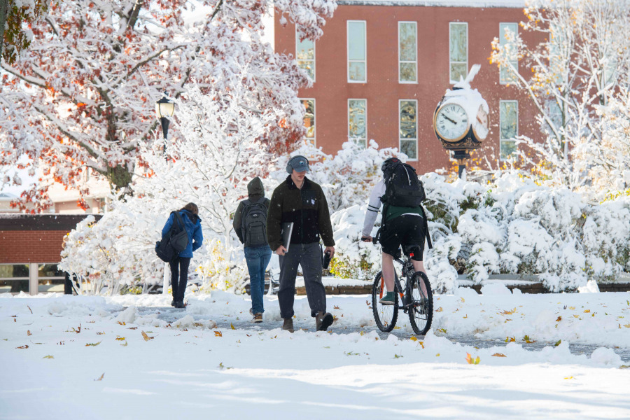 people walking or biking on snow covered walkway on university campus