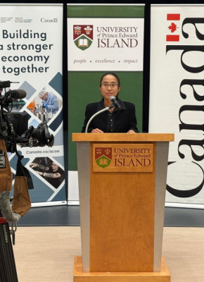 Dr. Beibei Jia, Assistant Professor, Epidemiology, AVC, speaks at the news conference announcing funding for shellfish health research and resilience projects. Photo of a woman standing at a podium flanked by video cameras