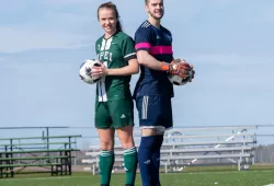 A female and a male soccer player stand back to back