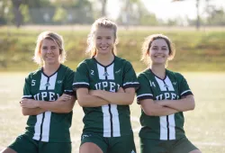 Three smiling female soccer players