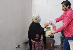 A man hand-delvers a basket of food to an older woman