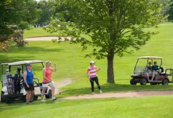 A scene on a golf course from a previous Panther Golf Classic. A pair of female golfers celebrate a shot, out of frame, with their arms in the air.