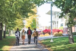 Photo of four students walking along a campus pathway