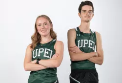 A female and male athlete post for the camera with crossed arms, looking tough