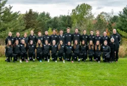 A large group photo of two rows of runners, male and female, wearing black UPEI cross-country track suits