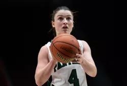 A female basketball player in a green and white Panthers uniform concentrates on a free-throw attempt