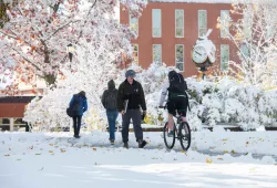 people walking or biking on snow covered walkway on university campus