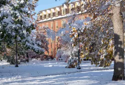 photo of brick building on campus with snow covered trees and foreground