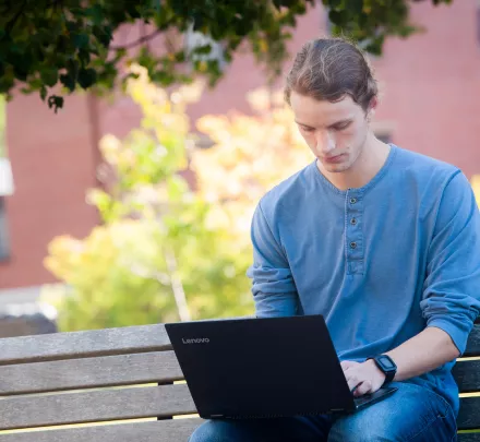 A student works on a computer on a bench