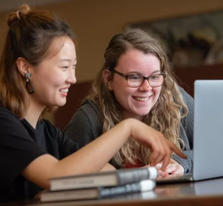 two students looking at a laptop computer