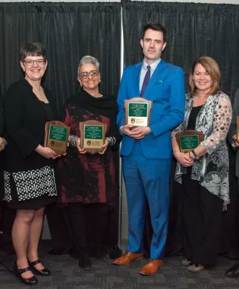 six award winning professors holding award plaques