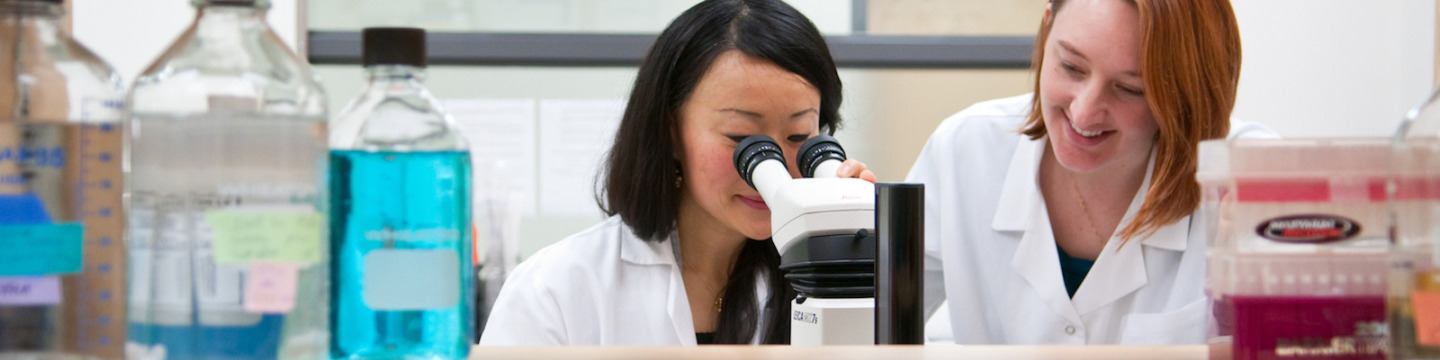 female biologists looking into microscope