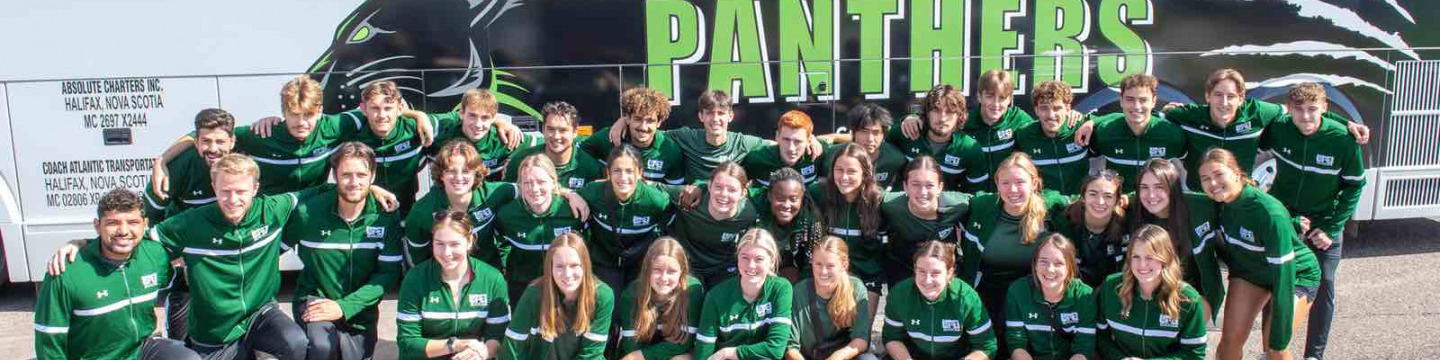 a large group of UPEI Panther athletes posing in front of a bus with "Panthers" on the side