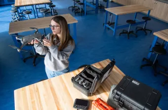 UPEI climate change student Zoe Furlotte examining a small drone in a laboratory