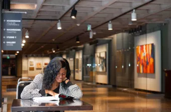 a female student sitting and reading in a gallery