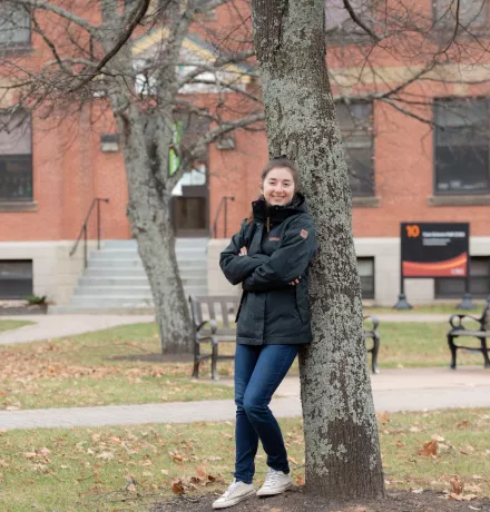 upei math graduate shannan hill leaning on a tree in front of cass science hall