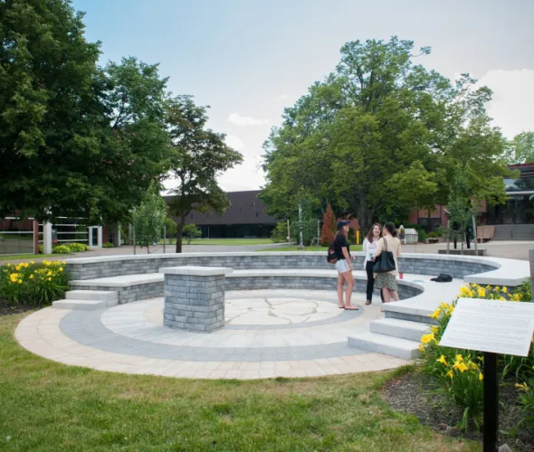 Photo of three students standing in an outdoor amphitheatre on campus
