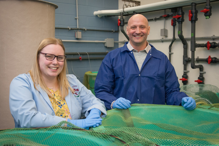 Veterinary student Alyson Brown and Dr. Mark Fast in AVC's aquatic animal facility A student and researcher stand at a large fish tank