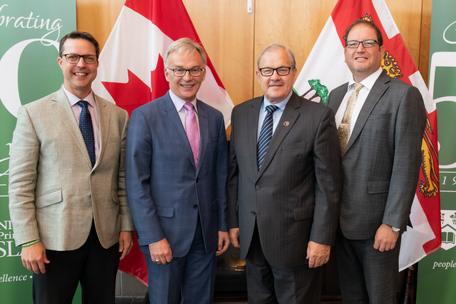 The Honourable Brad Trivers, Member of Parliament Sean Casey, the Honourable Lawrence MacAulay, and Dr. Adam Fenech Four men stand before the Canada and PEI flags