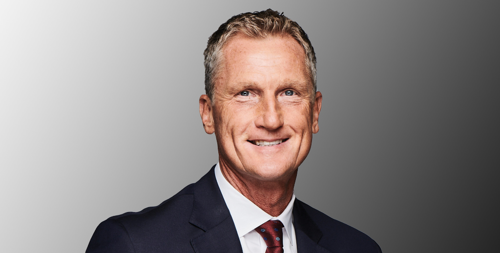 A close-up photo of a smiling man in a suit