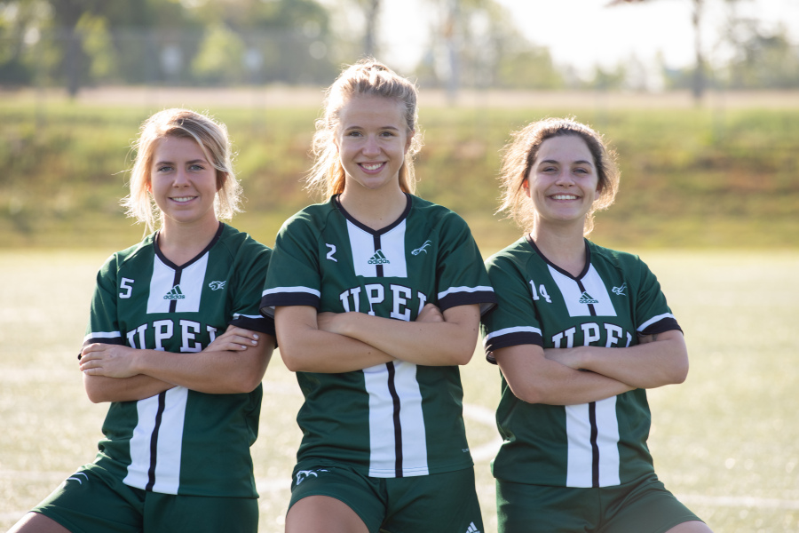 Three smiling female soccer players
