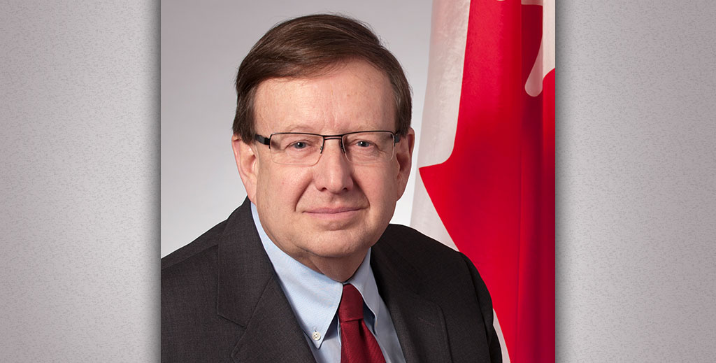 A portrait of an older man in front of a Canadian flag