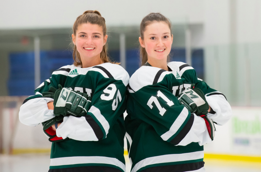 Two female hockey players stand back to back