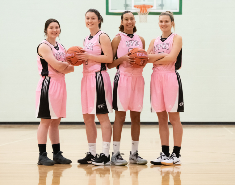 Four female basketball players in pink uniforms