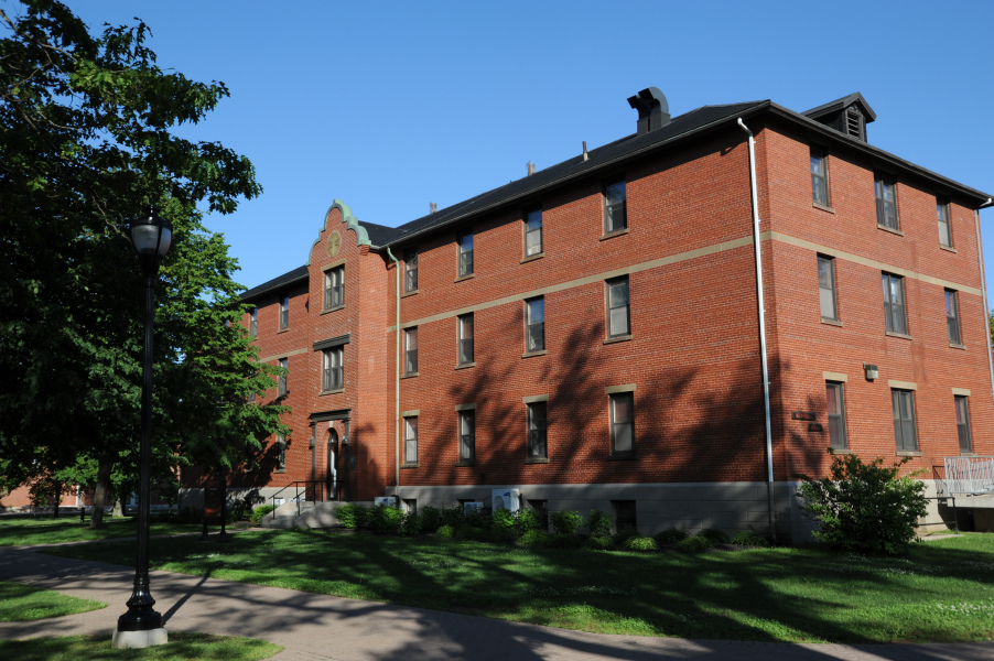 UPEI's Memorial Building A brick building with shadows of leaves on the front on a sunny day