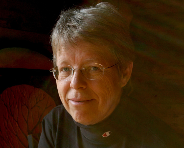 A photo portrait of a woman with shorter hair and glasses