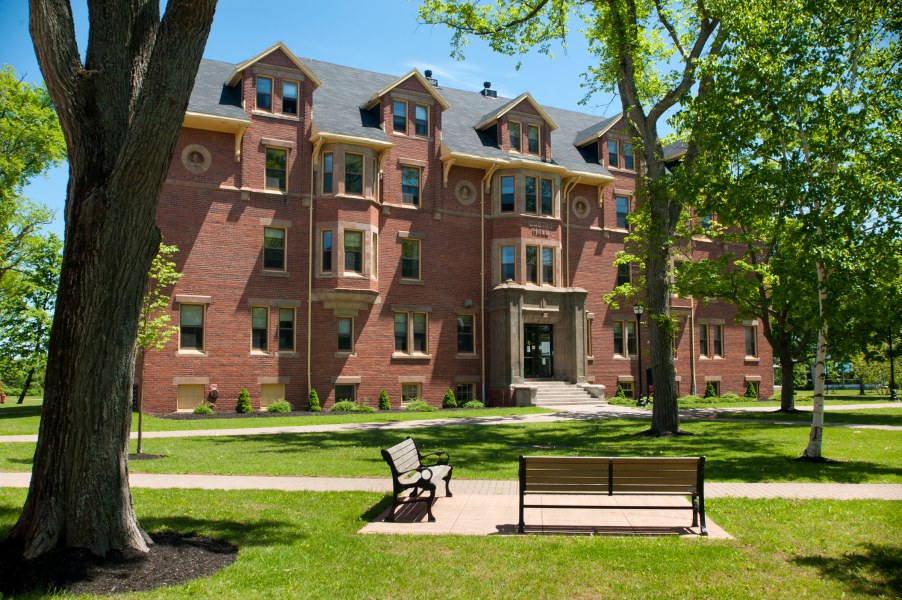 A four-storey brick building with lush trees around it