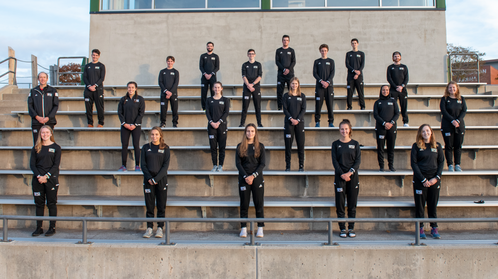 A group of male and female student athletes standing in formation on a set of bleacher seats