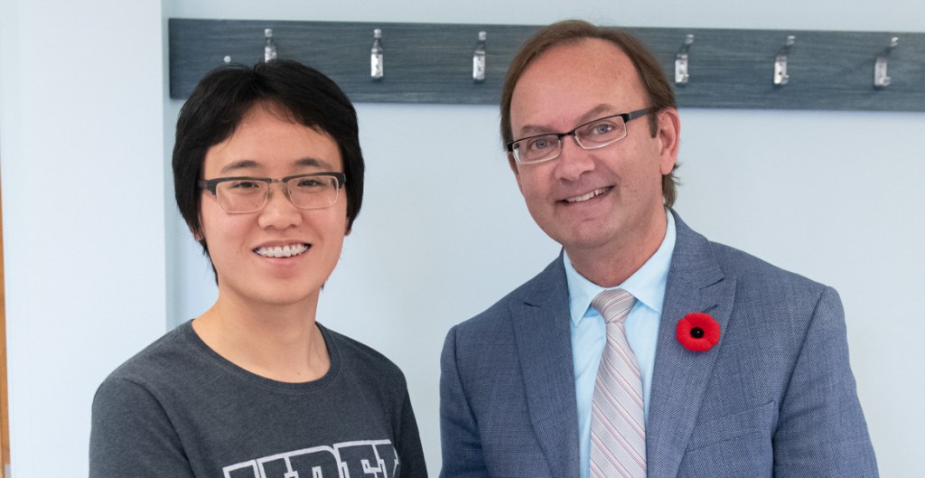 Han Xu and Dr. Ronald MacDonald, dean of the Faculty of Education at UPEI A smiling young woman with short dark hair and a smiling older man