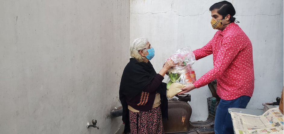 A man hand-delvers a basket of food to an older woman