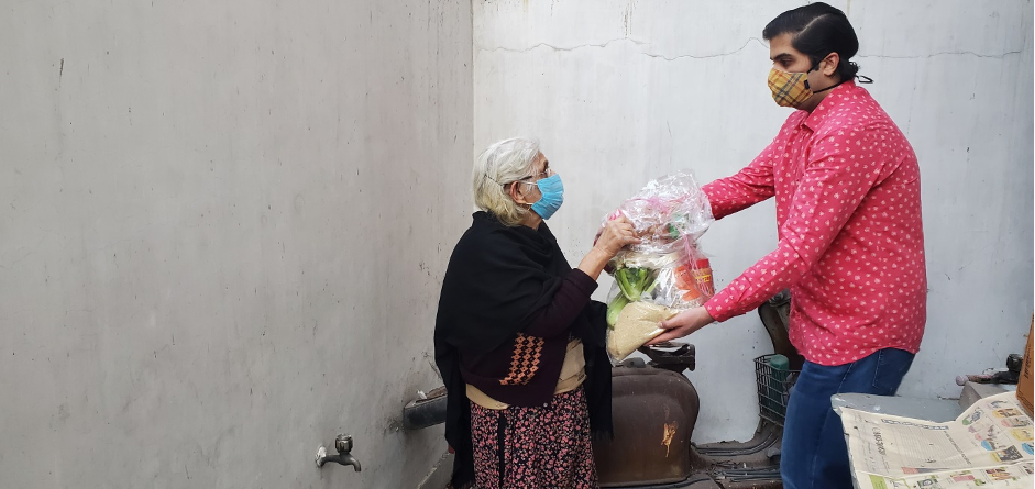 Sidharth Dhar delivers a ration kit in Delhi, India A man hand-delvers a basket of food to an older woman