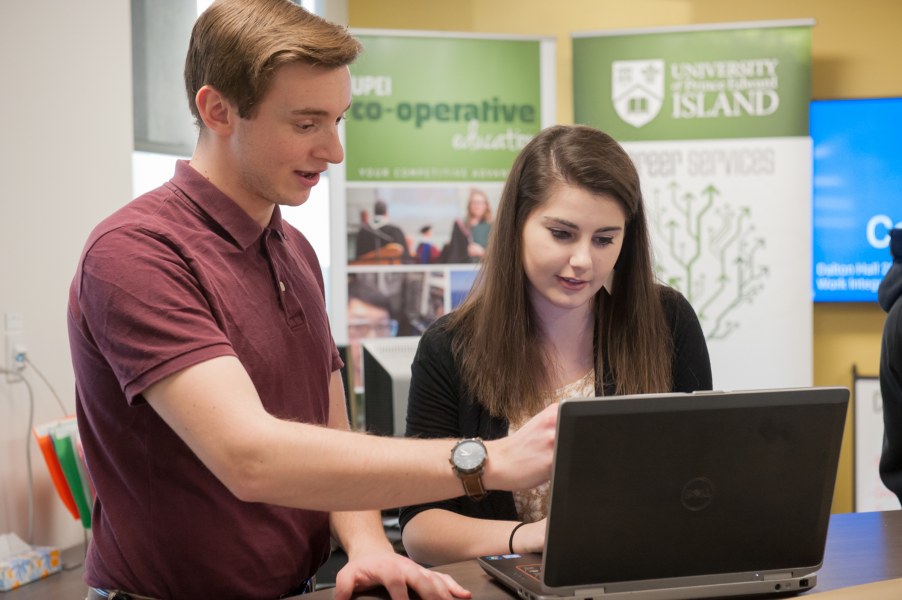 A male career counsellor points to a laptop screen of a female in a room marked "Career Stuido"