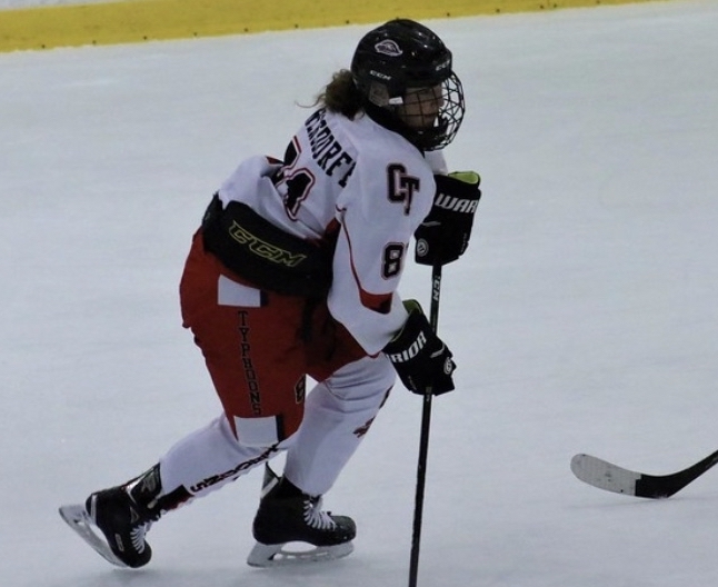 a female hockey player skates up the ice with a puck