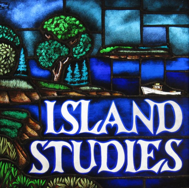 A stained glass window portraying an island scene with sky, land, trees, and the sea. The words "Island Studies" are prominent in the foreground. 