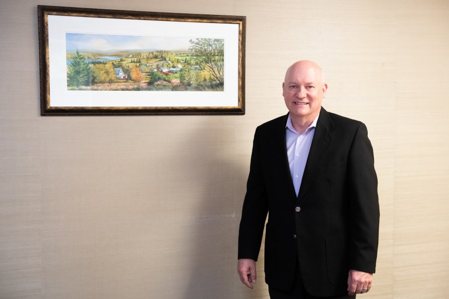 Photo of Dr. Greg Keefe standing by a painting at the Atlantic Veterinary College at UPEI