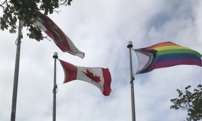 Photo of PEI, Canada and Progress Pride flags flying on poles on the UPEI campus