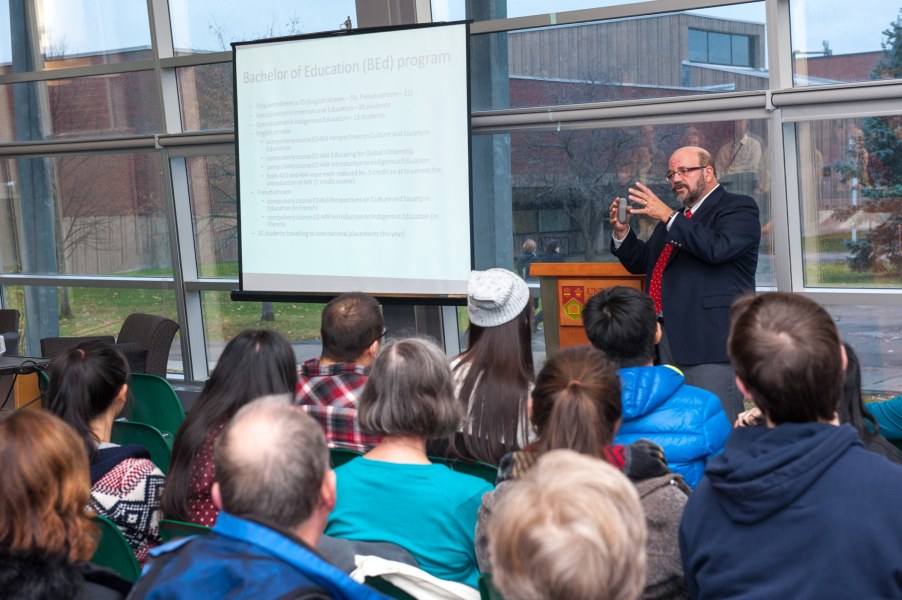 Man presenting to an audience using a projection screen