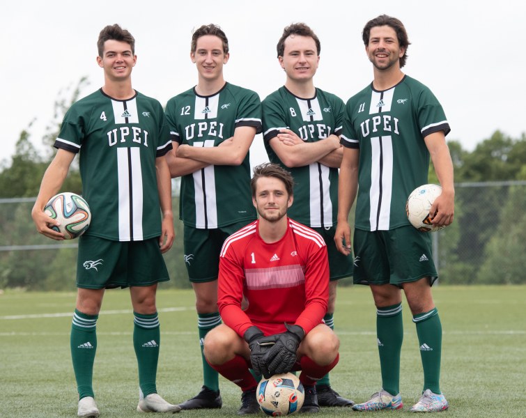A squad of male soccer players pose for the camera with goalie kneeling in the foreground