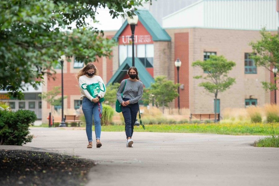 Two women wearing non-medical masks walking on the UPEI campus