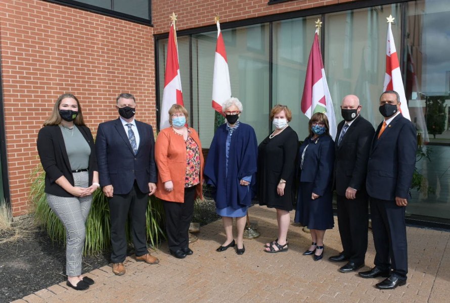 Ms. Samantha MacLean, President, UPEI Student Union; The Honourable Dennis King, Premier of Prince Edward Island; Dr. Margaret Steele, MD, Dean of the Faculty of Medicine, Memorial University of Newfoundland; The Honourable Catherine Callbeck, UPEI Chancellor; Ms. Marilyn Barrett, Director of the UPEI Health and Wellness Centre; Dr. Jo-Ann MacDonald, Dean of Nursing (Interim), UPEI; Dr. Greg Keefe, Dean of Veterinary Medicine, Atlantic Veterinary College, UPEI; Dr. Alaa Abd-El-Aziz, UPEI President and Vice-Chancellor A group photo of men and women standing in front of an array of flags from PEI and Canada