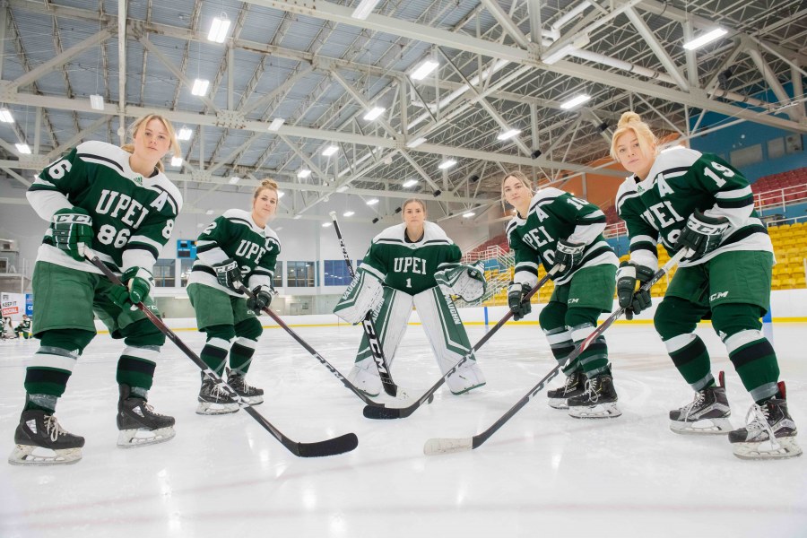 group photo of five women hockey players holding their sticks
