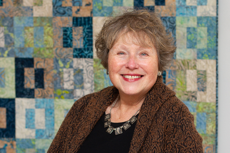 photo of woman with a quilt in background