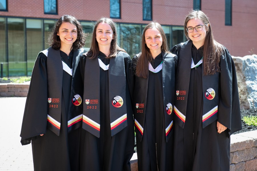Sisters Julia, Tiffany, Megan, and Madison Grounds, from Prince George, BC., celebrate their graduation at the convocation ceremony for the faculties of Arts, Education, and Graduate Studies on May 12. The sisters are wearing stoles presented to Indigenous graduates on Monday, May 10, as a visual symbol of accomplishment and pride in their heritage. The double curve represents the Mi'kma'ki First Nations, the infinity symbol represents the Métis Peoples, and the polar bear represents the Inuit while the crest on the stole features the four sacred colours: white, yellow, black, and red. Graduates and sisters Julia, Tiffany, Megan, and Madison Grounds