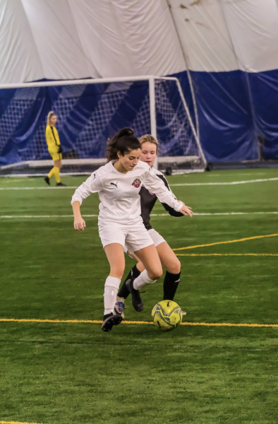 photo of woman dribbling soccer ball with opponent nearby