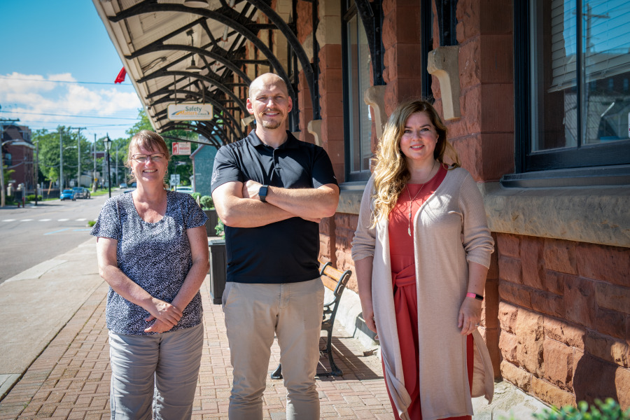 Barbara Rousseau, Dr. Josh MacFadyen, and Natalie Munn stand next to the former Charlottetown Railway station.